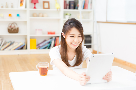 部屋でタブレットを見る女性
